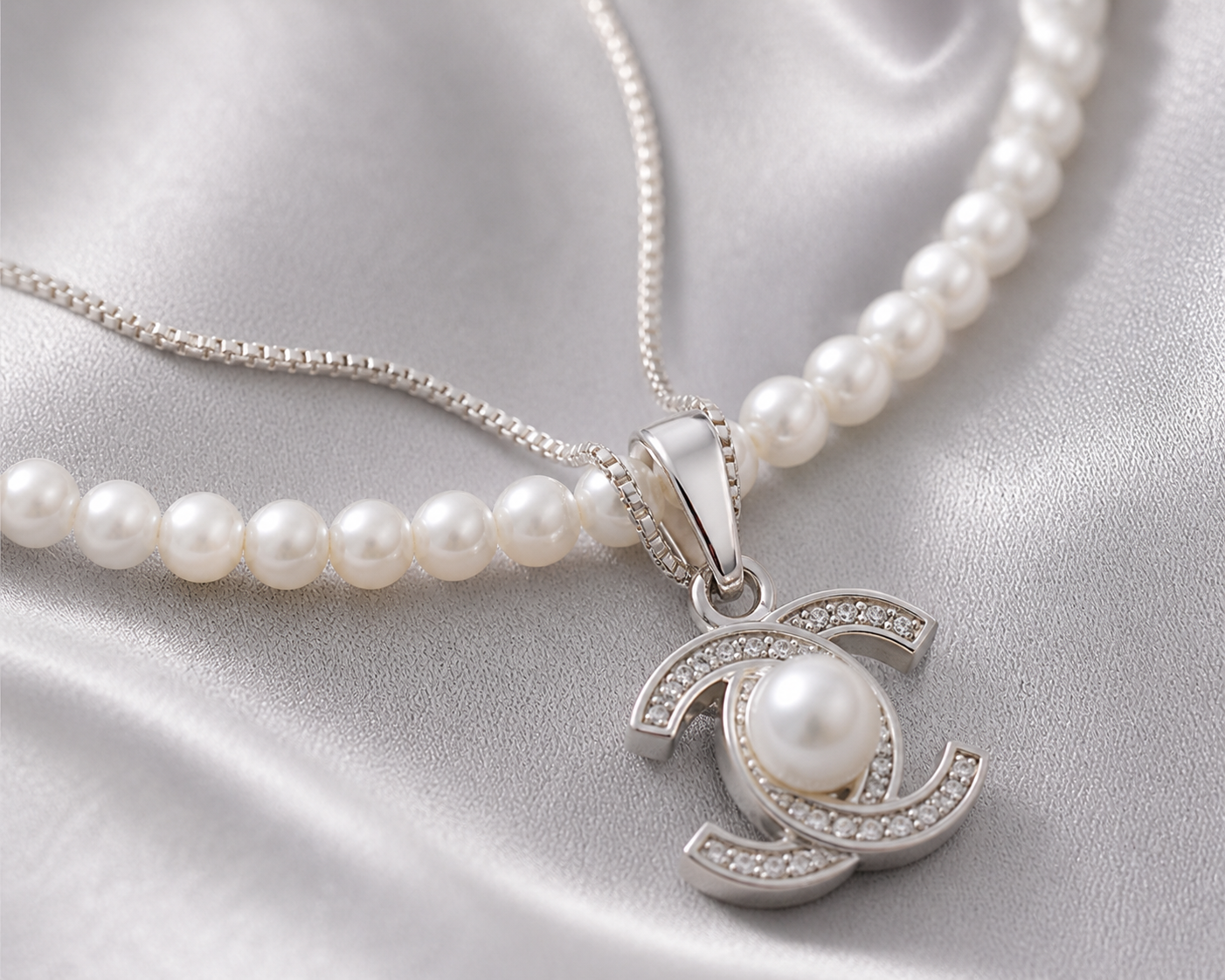 Pearl necklace with a silver pendant on a satin surface